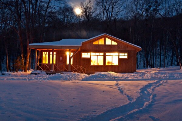 Casa calda nella foresta invernale. Serata tranquilla nel bosco