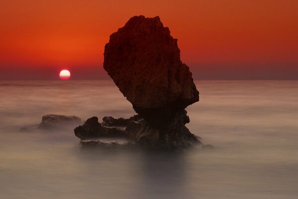 Puesta de sol en el fondo de un acantilado en el mar