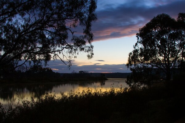 Amanecer en la orilla del lago. Reflejo de las nubes en el agua