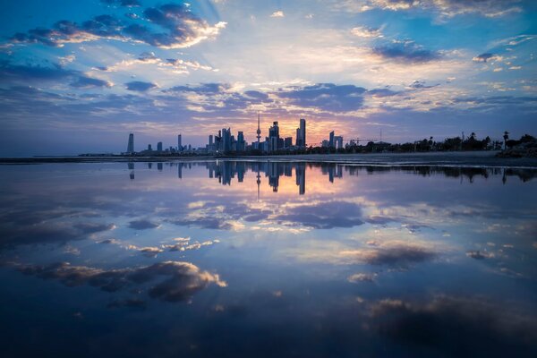 La ciudad y las nubes se reflejan en el cuerpo de agua