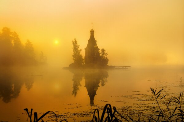 Iglesia envuelta en niebla sobre el agua