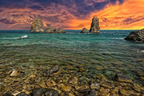 Cielo ardiente sobre la costa rocosa del mar