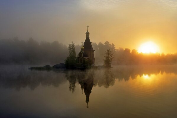 Reflexion der Kirche bei Sonnenuntergang im Nebel