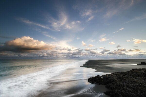 The sea sandy shore is washed by waves