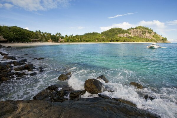 Rocky shore, azure foam water and a hilly island in the distance