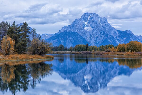 A beautiful mountain landscape with an autumn forest reflected in the calm surface of the lake