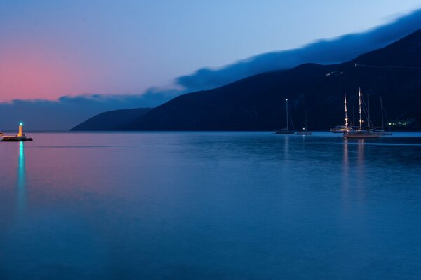 Tramonto dalla baia. Luce verde del faro in lontananza