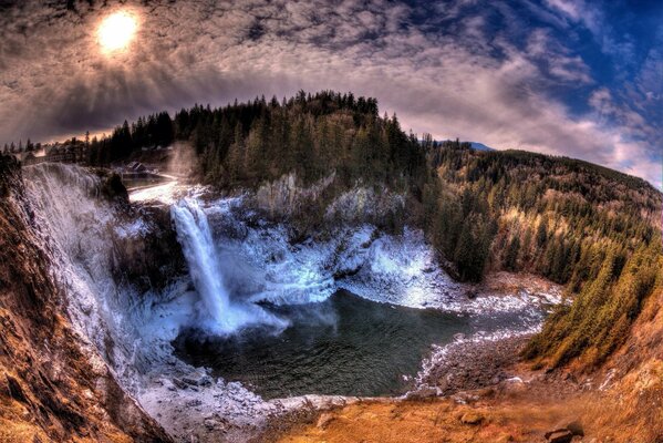 Cascada. Bosque y montañas. Nubes