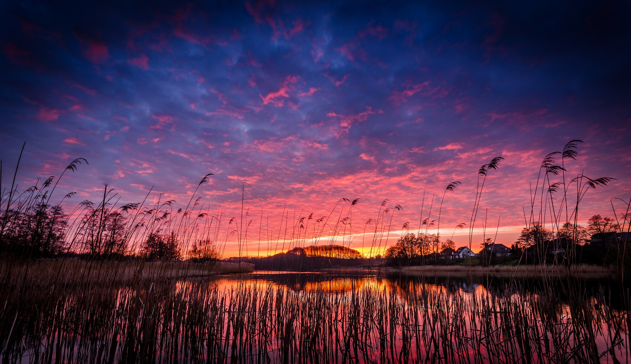 noche pueblo lago orilla hierba árboles naranja carmesí puesta de sol azul cielo nubes reflexión