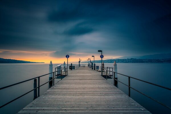 Wooden plank bridge on the river in the rays of the almost sundown