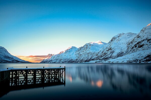 Seebrücke am See und schneebedeckte Berge