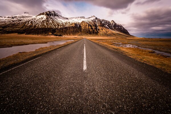 Una strada deserta che conduce alle montagne innevate