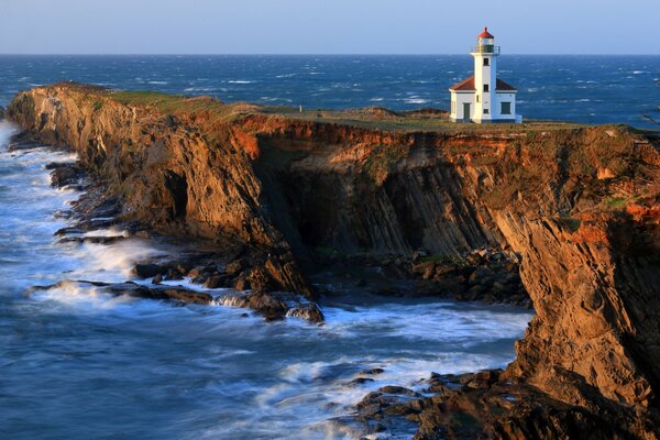 Hermosa vista del faro rompiendo en la costa rocosa de las olas