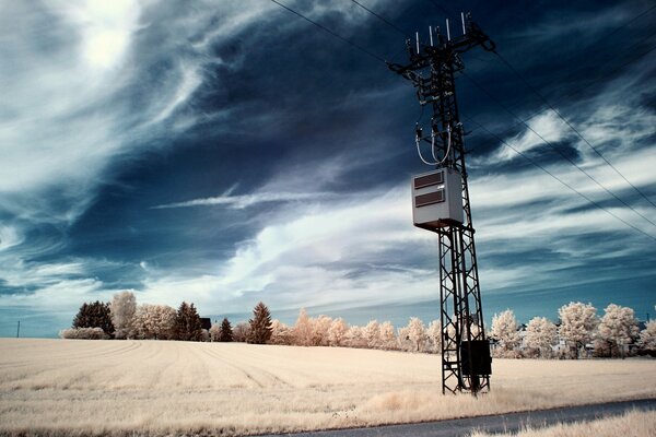 A pole with electric wires on the background of a cloudy sky