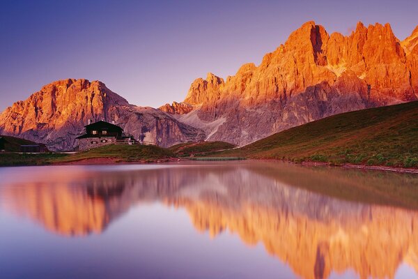 A house on the ridge of a mountain with a lake