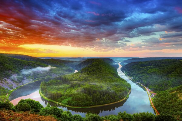 Bunter Himmel über Wald und Fluss