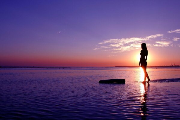 Foto di una ragazza in mare sullo sfondo del tramonto