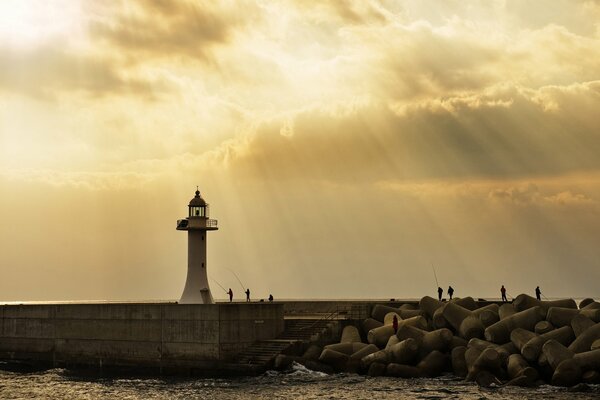 Fishing on the seashore at the lighthouse under the rays of the sun