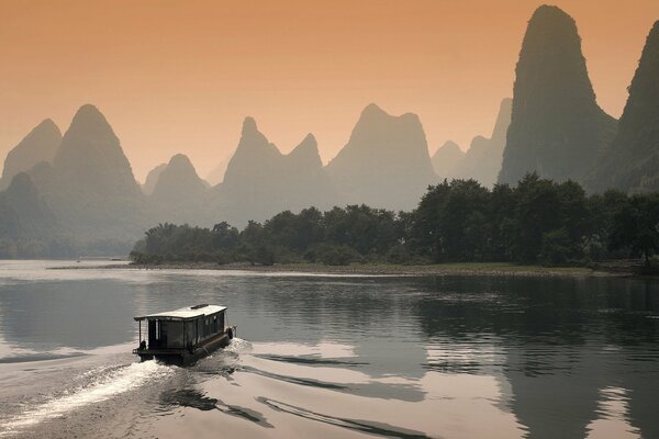 The boat sails at sunset on the river