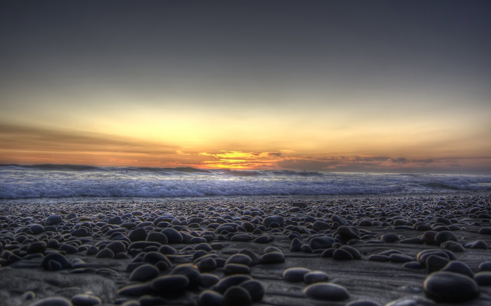 piedras guijarros costa mar olas puesta de sol