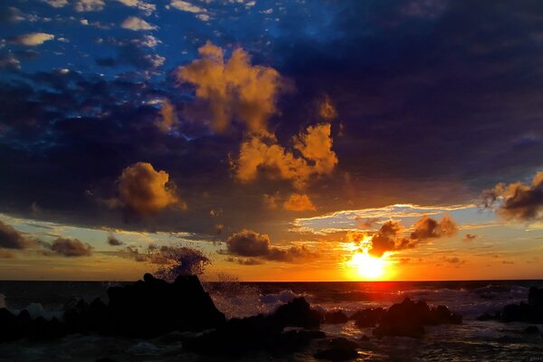 Hermosa puesta de sol entre las nubes sobre la costa rocosa del mar