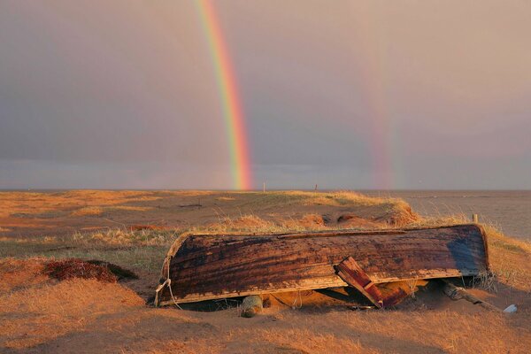 Umgekipptes Boot auf einer Sandbank auf einem Regenbogen-Hintergrund