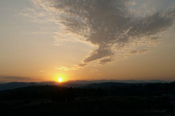 The dawn sun in the clouds over the mountains