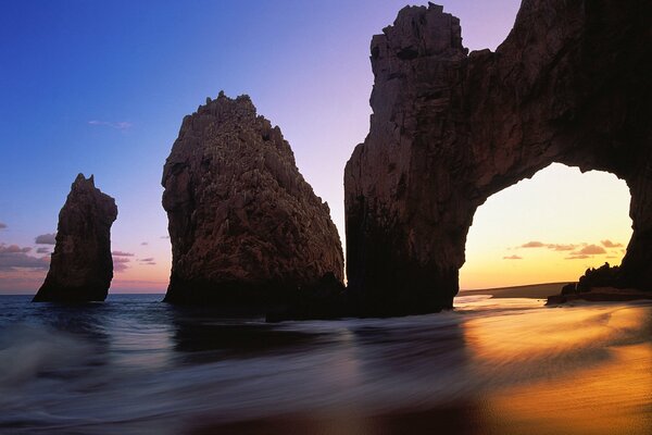 Montañas con olas de mar, puesta de sol