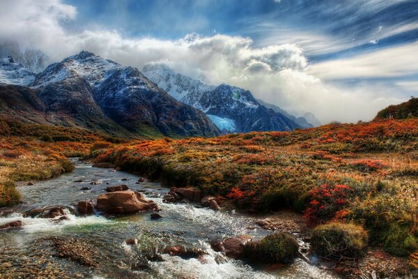 Gebirgsfluss und Gipfel in den Wolken