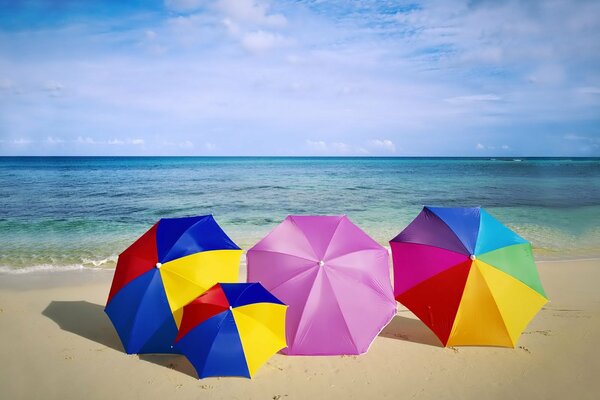 Parapluies multicolores sur la plage sur fond de mer bleue