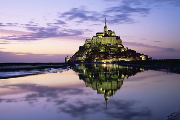 El castillo en la montaña refleja las luces del horizonte