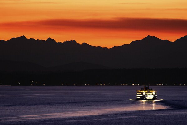 Evening ferry on the background of an orange sunset