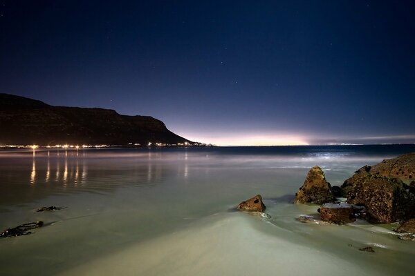 Rocky coast at night with city lights on the horizon