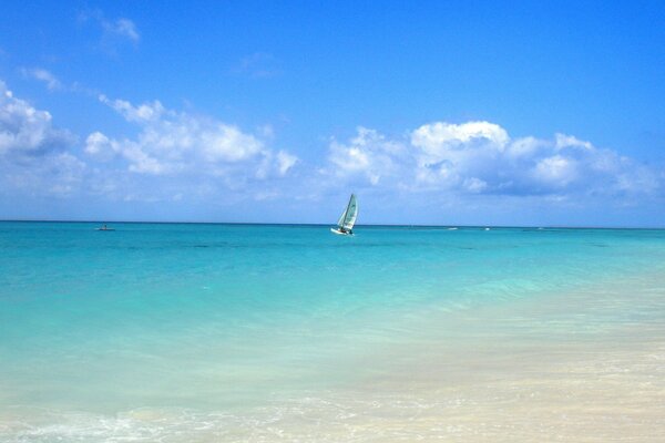 Ein kleines Segel am Horizont des blauen Meeres