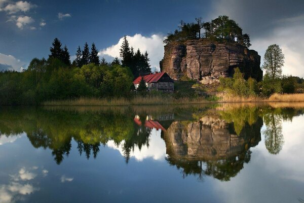 Ein einsames Haus unter einem Felsen am See