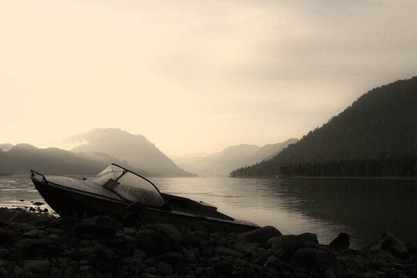 Lake in the mountains. Black and white boat on the rocks