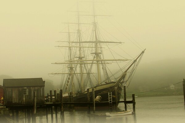 Velero en la niebla en el muelle de madera