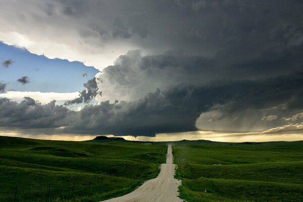 Grüne Straße durch Hügel und Wolken