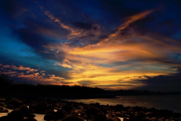 Tramonto sulla riva con rocce e nuvole