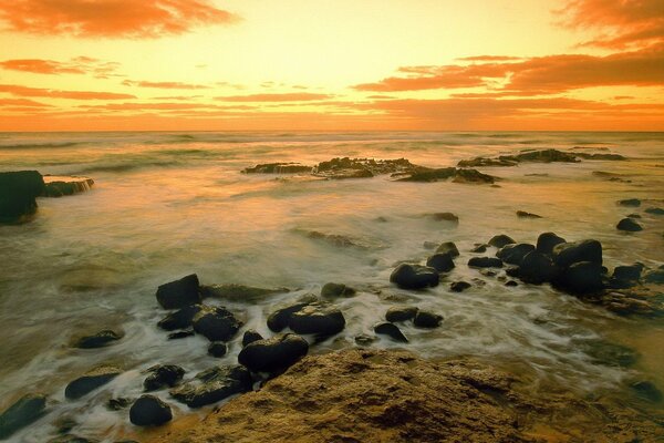 Piedras de mar en la orilla al atardecer