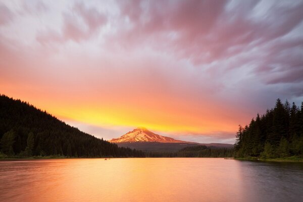 Lake at sunset and mountains in the clouds