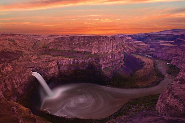 Waterfall by the river in a mountain gorge