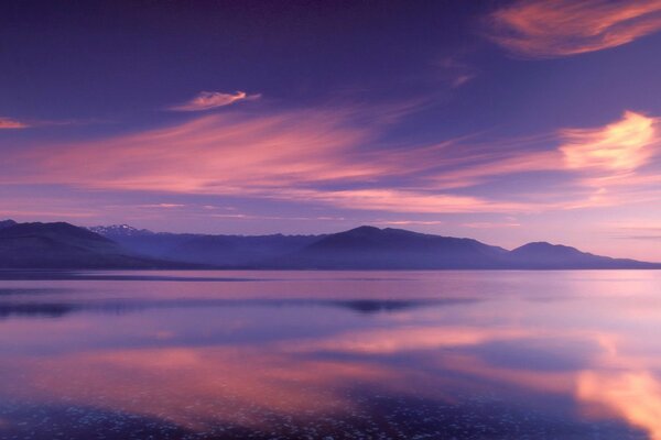 Nuages roses se reflètent dans le lac de montagne