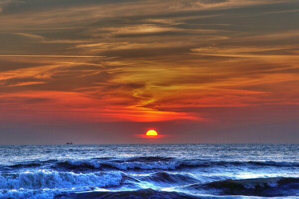 Olas en el mar y puesta de sol en tonos carmesí