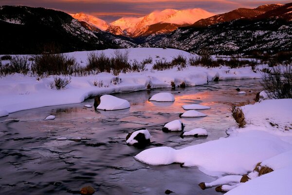 Winter Fluss in den Bergen mit Sonnenuntergang im Hintergrund