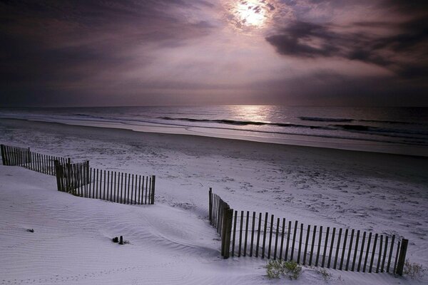 Strand mit weißem Sand und einem Zaun aus Ästen