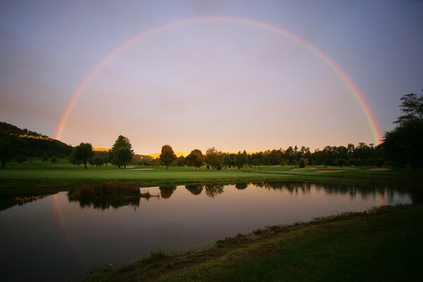 The rainbow stretches across the lake and meadow