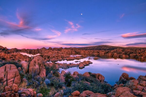 Lago con costas rocosas en el fondo de la puesta de sol