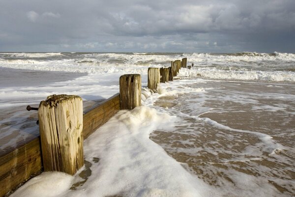 Schaumwellen im Meer am Zaun