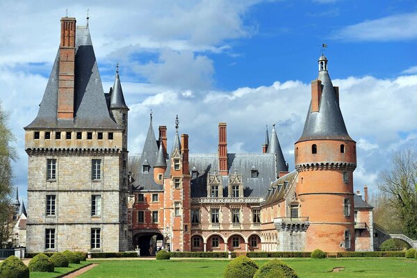 A castle with a green garden and a cloudy sky